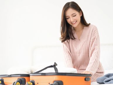 Woman happily packing a suitcase
