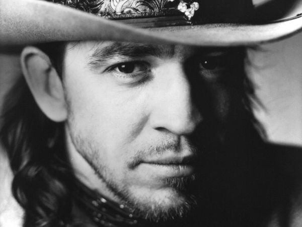 Black and white close-up of a man wearing a decorated cowboy hat.