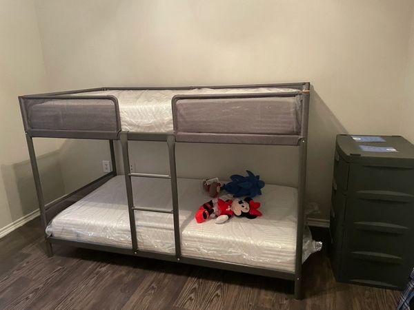 Children's metal twin bunk bed assembled with mattresses.