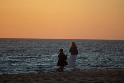 Man proposing to a woman on the beach at sunset