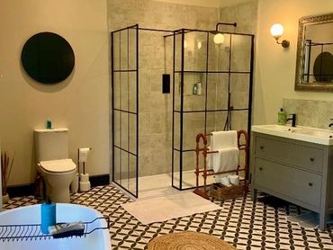 Modern bathroom with geometric tile floor, glass shower, and freestanding tub.