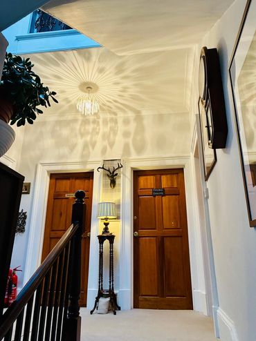 Elegant hallway with wooden doors, decorative lamp, and intricate ceiling light shadows.
