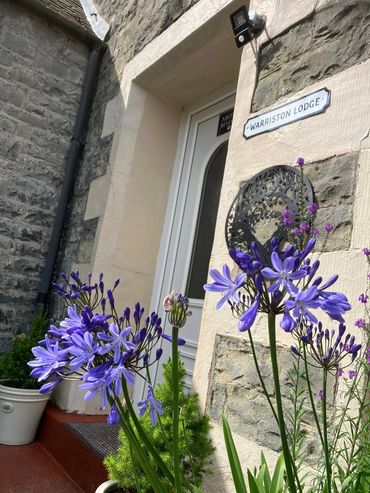 Purple flowers bloom near the entrance of Warriston Lodge.