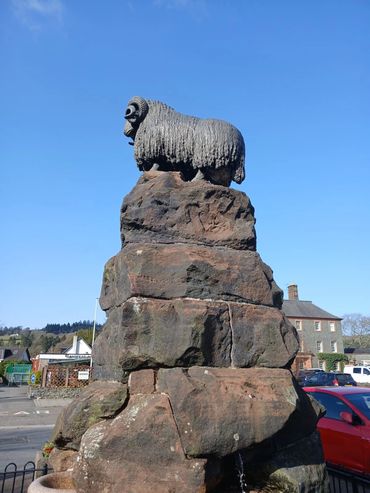 Statue of a ram atop a large stone pedestal under a clear blue sky in moffat dumfries and galloway.