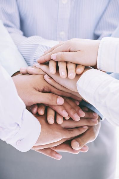 Multiple hands stacked together symbolizing unity and teamwork.
