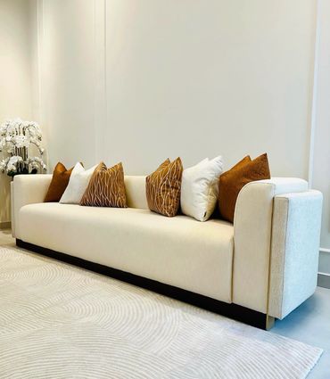 Modern beige sofa with brown and white cushions in a minimalist living room.