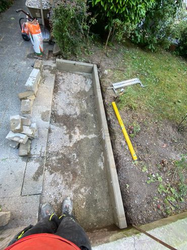 Construction work on a garden path with bricks and tools scattered around.
