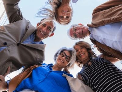 Happy group of older adults looking down at the camera, smiling.