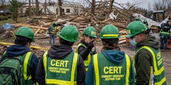 CERT members assess tornado damage among fallen trees and debris.