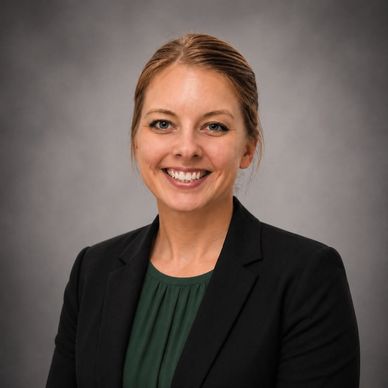 Professional woman smiling in business attire against gray background.
