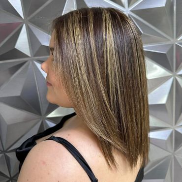 Woman with highlighted straight hair in front of a geometric wall.