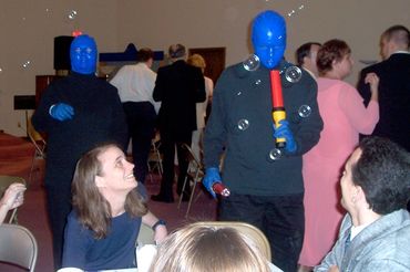 blue man group looks at the orange wand and bubbles