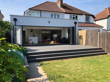 Modern house extension with open bi-fold doors to a spacious garden deck.