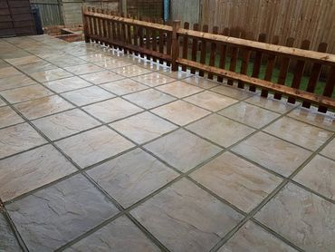 Wet tiled patio with wooden fencing in a backyard.