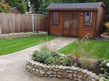 Well-maintained garden with a stone planter and a wooden shed at the back.