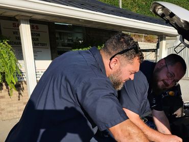 Two men installing a battery in a car