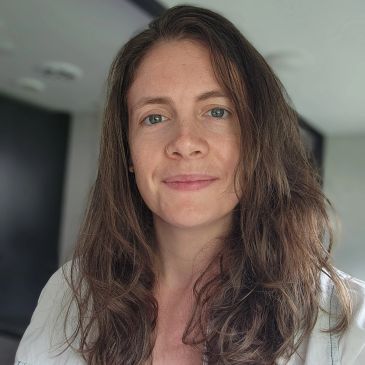 Woman with long brown hair smiling gently at the camera.
