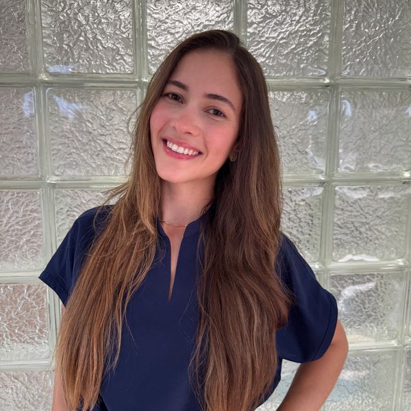 Smiling woman with long hair in front of a glass brick wall.