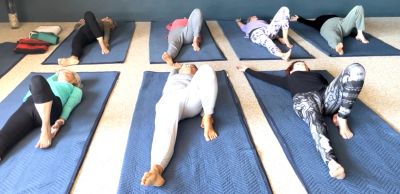 Group of people practicing yoga lying on mats indoors.