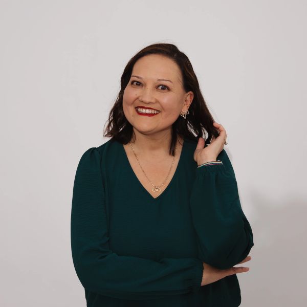 Smiling woman in green top touching her hair.