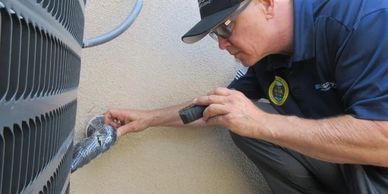 Technician inspecting HVAC system with flashlight.
