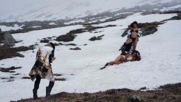 Photographer capturing models in swimwear on snowy terrain.