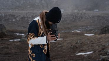 Man taking a photo with a vintage camera in a rocky area.