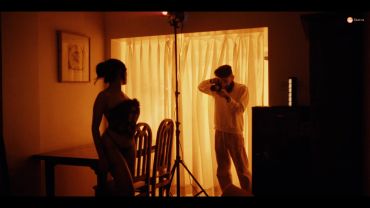 Photographer capturing model in warm-lit room.