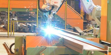 Robot welding metal beams in factory.
