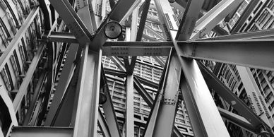 Black and white photo of intersecting steel beams in a building under construction.