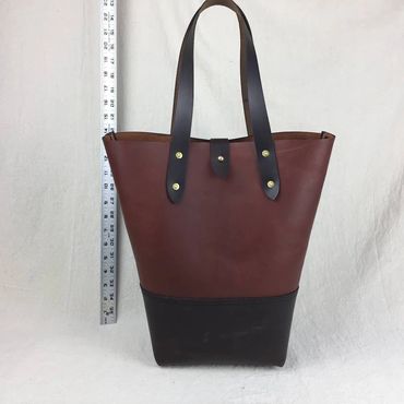 Two tone Brown leather tote with dark bown leather bottom with shoulder straps and leather tassel.