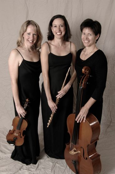 Three women in black dresses holding classical instruments: violin, flute, and cello.