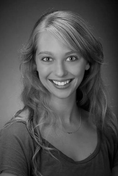 A headshot of Juliet Remmers with a broad smile and her hair down over her shoulders.