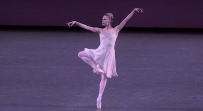 Sara Mearns on stage standing en pointe in retiré, her arms elongnaged and hands relaxed.