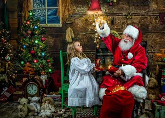 Santa bringing a magical gift to a visit with a little girl in front of a Christmas tree
