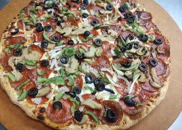A freshly baked pizza topped with pepperoni, olives, mushrooms, onions, and green peppers.