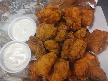 Crispy fried chicken nuggets with two cups of creamy dipping sauce.