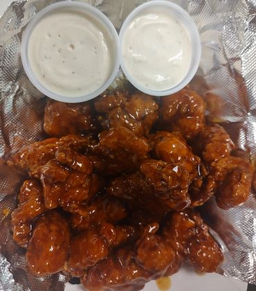 Sticky glazed chicken wings with two cups of creamy dipping sauce.