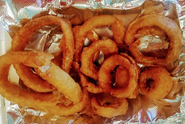 Golden crispy onion rings on a foil-lined tray.