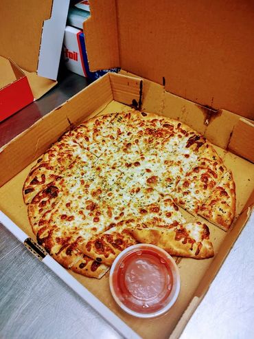 Cheese pizza with dipping sauce in a delivery box.