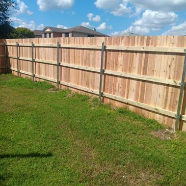 New wooden fence panels installed in a backyard on a sunny day.