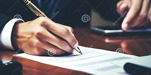 A person signing a document with a pen, holding a phone nearby.