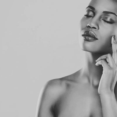 A serene black and white portrait of a woman with closed eyes and a gentle touch on her face.