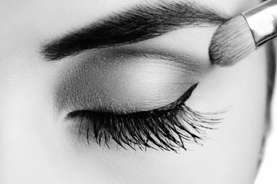 Close-up of an eye with makeup brush applying eyeshadow.
