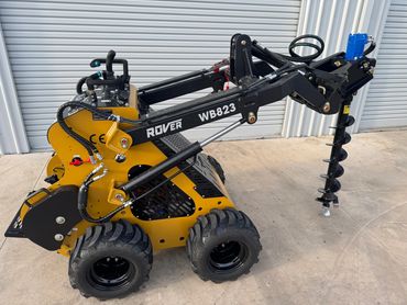 Compact Rover WB823 mini loader with auger attachment for drilling.
