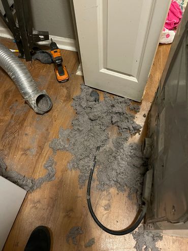 A laundry room showing the lint removed from the dryer vent.