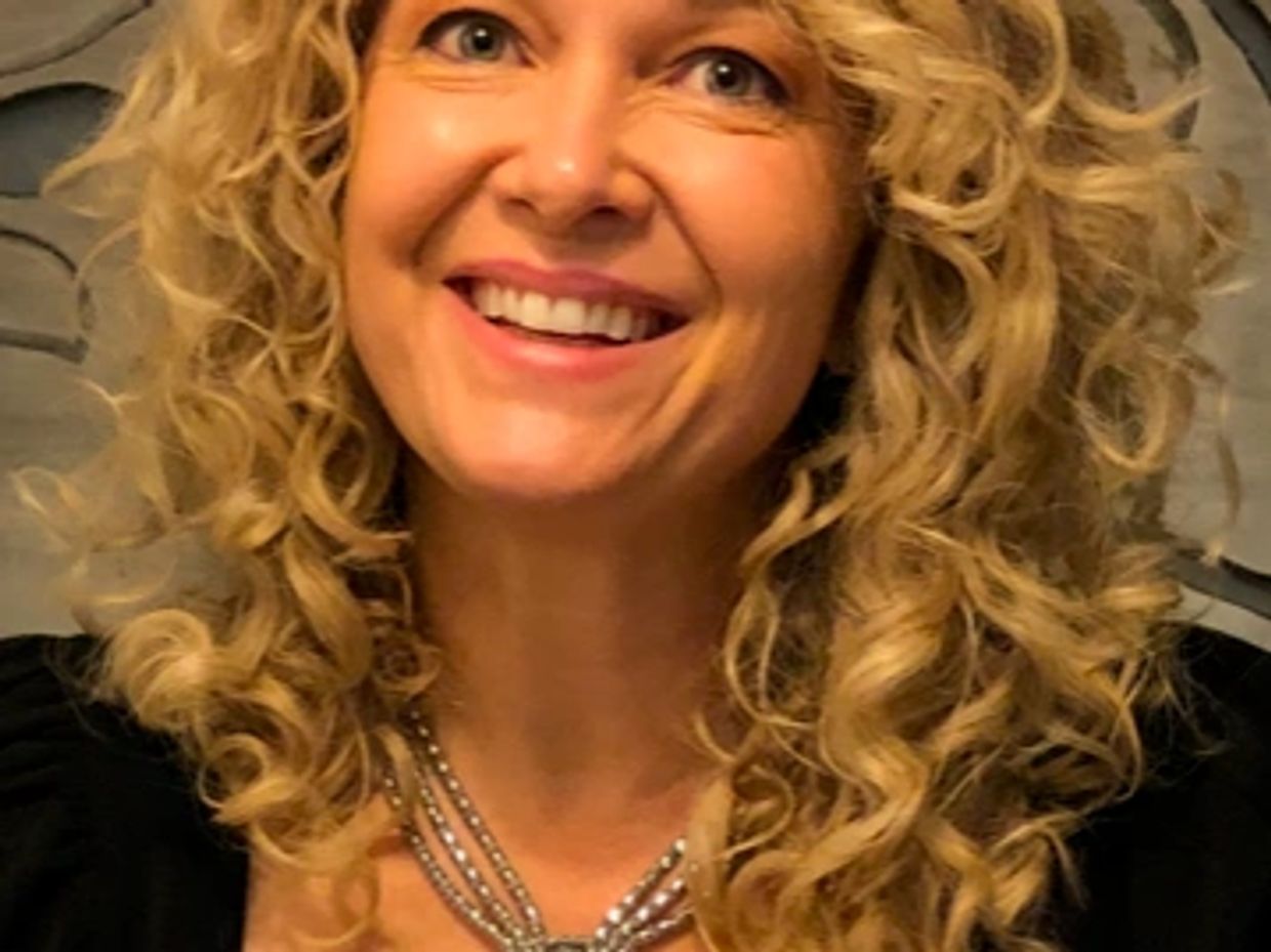 Smiling woman with curly blonde hair.