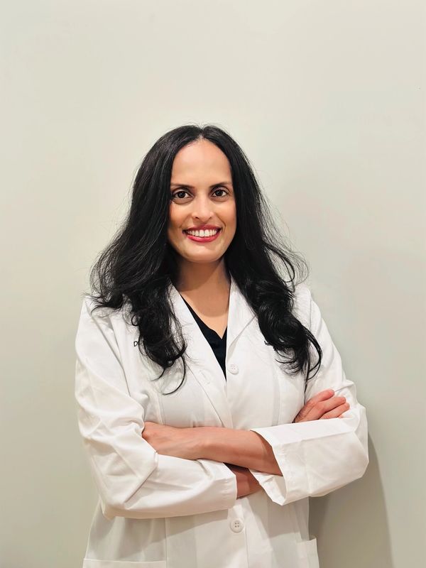 Smiling female doctor in a white coat with arms crossed.