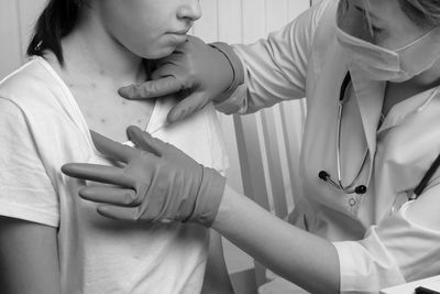 Doctor examining skin rash on patient's chest with blue gloves.