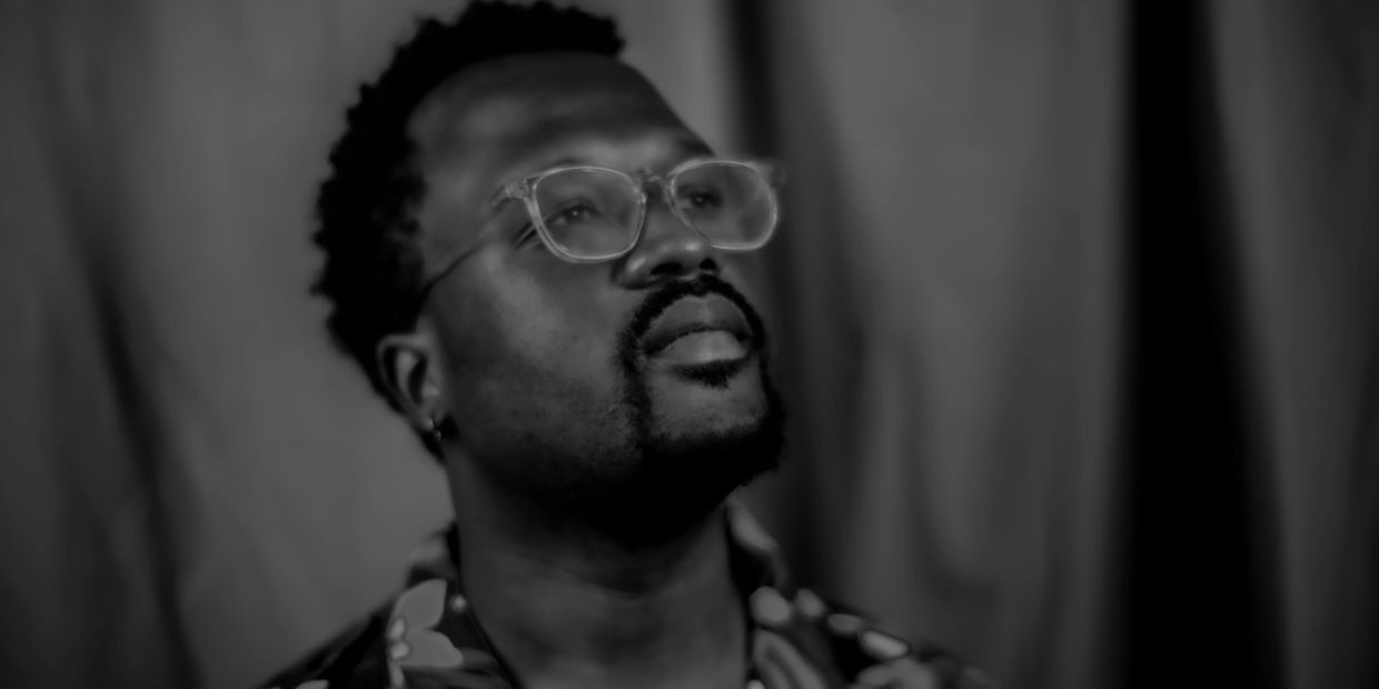 Black and white portrait of a man with glasses looking upward.